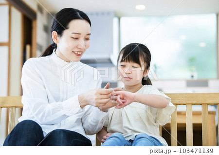 娘に絆創膏を貼る母親 103471139
