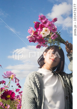 コスモス畑で花束を持って立つ女性 103473277