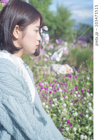 コスモス畑で座っている女性 103473515