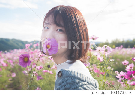 コスモス畑でコスモスを持つ女性 103473518