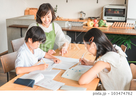 家で夏休みの宿題を手伝う母親と勉強する子供達 103474762