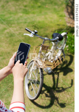 自転車とスマホを操作する女性の手元写真 103475612