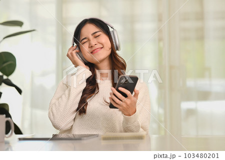 Joyful young woman listening to music in wireless headphones, enjoying favorite playlist. People, technology and lifestyle Joyful young woman listening to music in wireless headphones, enjoying favorite playlist. People, technology and lifestyle 103480201