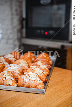Sprinkle the finished croissants on a baking sheet with almond flakes 103482772