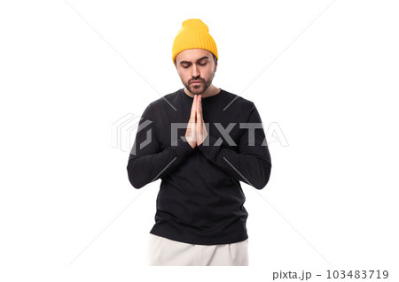 young brunette European brutal man in a black jacket prays and hopes 103483719