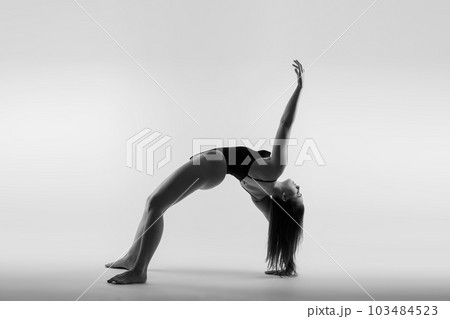Image of young plump female doing acrobatic stunt, studio shot 103484523