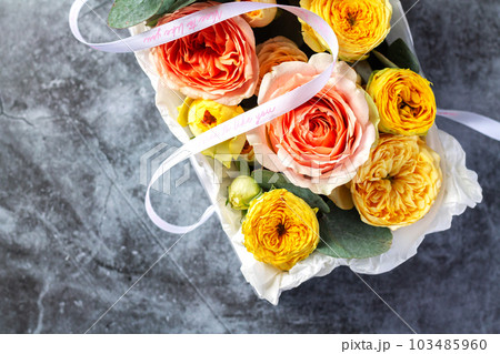 Gift box with bouquet flowers on stone table 103485960