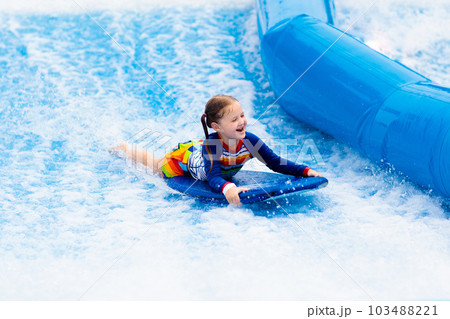 Little girl surfing in beach wave simulator 103488221