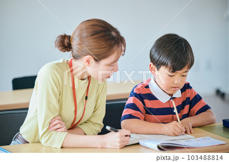 小学生の男の子と若い塾講師 103488814