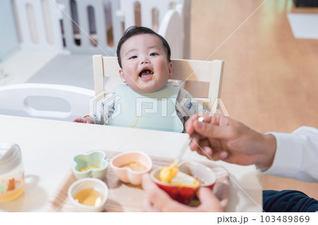 パパに離乳食を食べさせてもらってご機嫌な生後8か月の赤ちゃん パパに離乳食を食べさせてもらってご機嫌な生後8か月の赤ちゃん 103489869