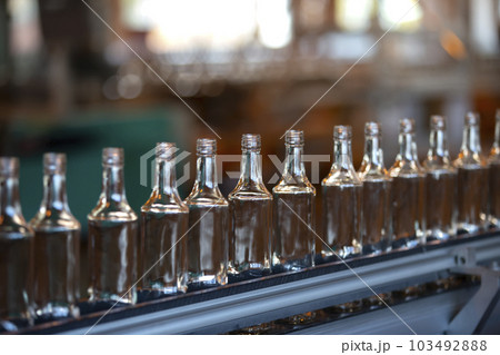 Glassworks. Glass industry. Many glass bottles on a factory conveyor. 103492888
