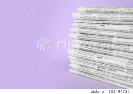 Stack of newspapers on light violet background, space for text. Journalist's work 103494786