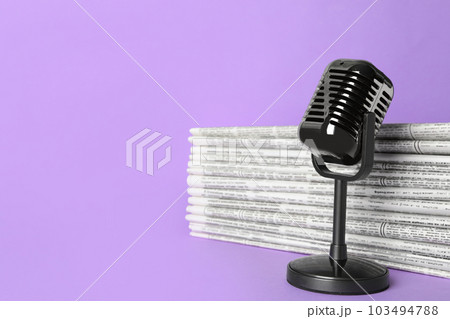 Newspapers and vintage microphone on light violet background, space for text. Journalist's work 103494788