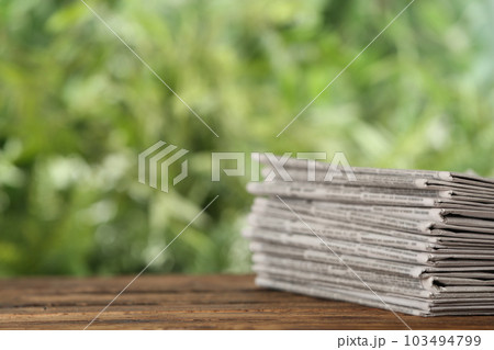 Stack of newspapers on wooden table against blurred green background, space for text. Journalist's work Stack of newspapers on wooden table against blurred green background, space for text. Journalist's work 103494799