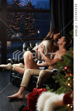 Passionate couple enjoying each other on sofa at home. Christmas celebration 103495939