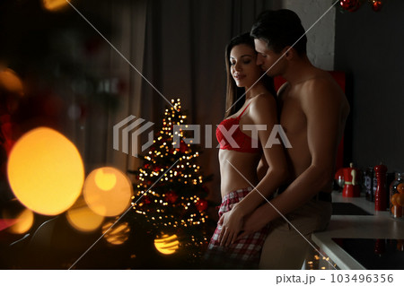 Passionate young couple enjoying each other in kitchen. Christmas celebration 103496356