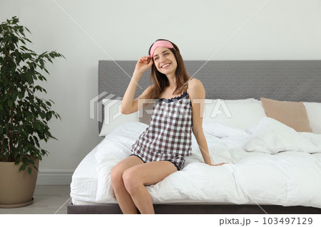 Beautiful woman wearing pajamas and sleep mask indoors. Bedtime 103497129