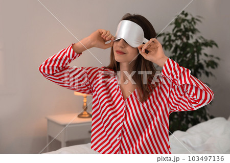 Beautiful woman wearing pajamas and sleep mask indoors. Bedtime Beautiful woman wearing pajamas and sleep mask indoors. Bedtime 103497136