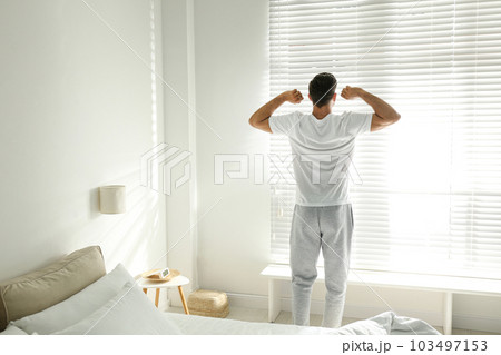 Man near window in bedroom. Lazy morning Man near window in bedroom. Lazy morning 103497153