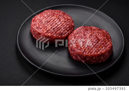 Fresh raw ground beef burger patty with salt and spices 103497391