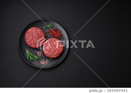 Fresh raw ground beef burger patty with salt and spices 103497441
