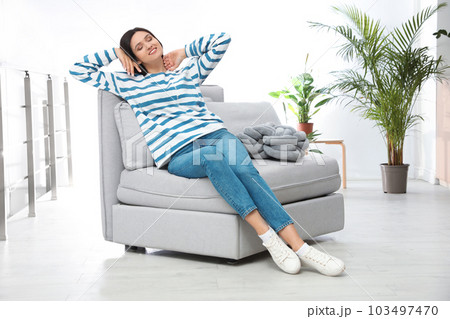 Young woman relaxing on couch at home Young woman relaxing on couch at home 103497470