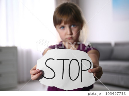 Abused little girl with sign STOP indoors, focus on hands. Domestic violence concept 103497758