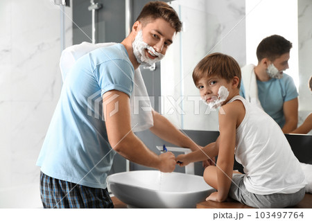 Dad and son washing razors in bathroom 103497764