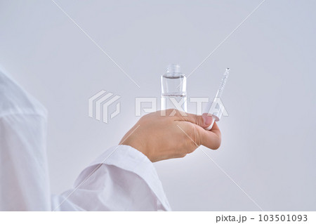Female hands hold a cosmetic serum with a dropper. 103501093