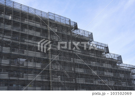 大規模修繕工事中の足場に囲われたマンションの外観 103502069