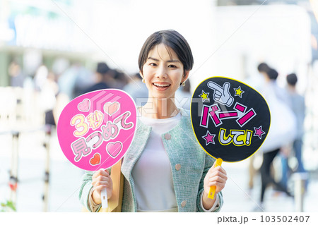 応援うちわを持ってライブ会場の前に立つ女性　推し活 103502407