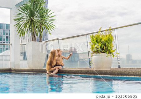 Mother and son in the pool among the skyscrapers and the big city. Relax in the big city. Rest from stress 103506805