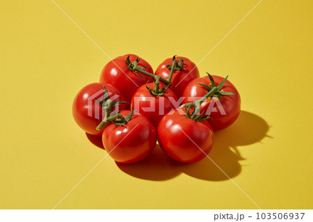 Against a yellow background, ripe fresh tomatoes decorated. Tomatoes contain a lot of vitamins A, C and B6 which are good for skin and hair Against a yellow background, ripe fresh tomatoes decorated. Tomatoes contain a lot of vitamins A, C and B6 which are good for skin and hair 103506937