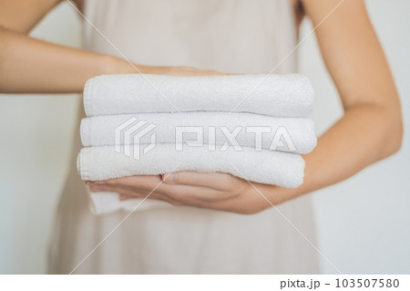 A woman is holding a stack of white towels. Concept of service in hotels, laundry, spa 103507580