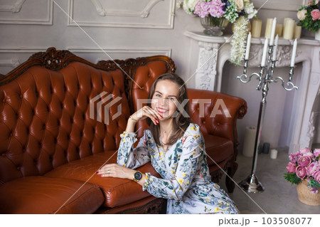 Young beautiful woman in floral dress sits on floor Young beautiful woman in floral dress sits on floor 103508077