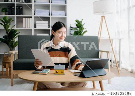 Young real estate agent worker working with laptop and tablet at table in home office and small house beside it. Young real estate agent worker working with laptop and tablet at table in home office and small house beside it. 103508598