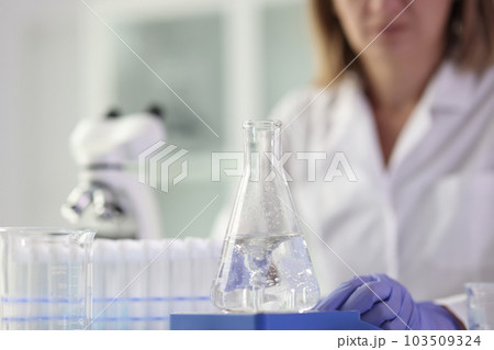 Chemist does research sitting near test tubes and flask Chemist does research sitting near test tubes and flask 103509324