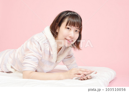 パジャマ姿でスマホを操作する女性 103510056