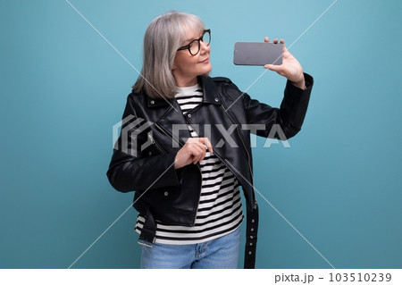 stylish modern 60s modern old lady granny with gray hair holding phone with mocap on bright 103510239