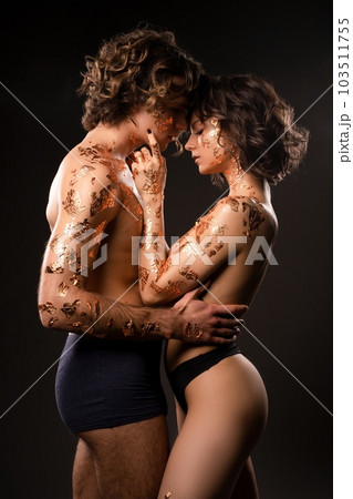 Sexy shirtless couple with body art hugging in black studio 103511755