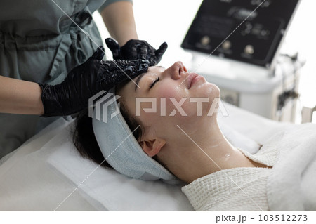 Beautician doctor applying cosmetic gel peeling mask cosmetology spa concept. 103512273