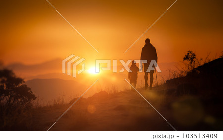 father and son in mountains at sunset. backlit. Happy father and son hiking at sunset mountains. Walk towards to goals and achievements father and son in mountains at sunset. backlit. Happy father and son hiking at sunset mountains. Walk towards to goals and achievements 103513409