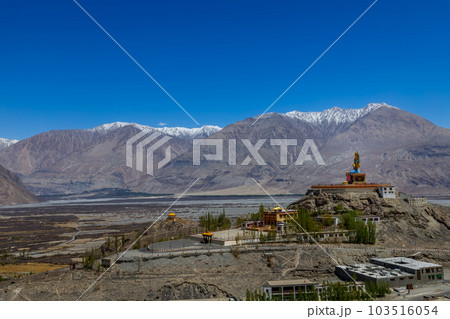 Big Sitting Buddha Statue at Diskit Monastery with Himalaya Range in the back - Nubra Valley, Ladakh, India. 103516054