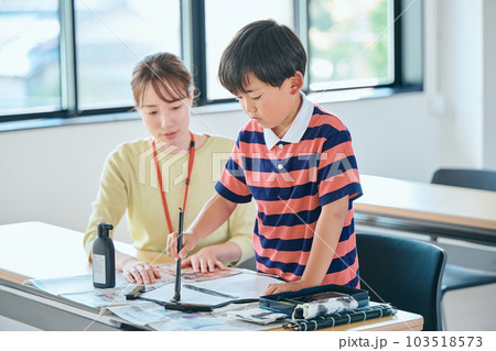 書道を練習する生徒と若い塾講師 103518573