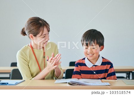 勉強する生徒を褒める若い塾講師 勉強する生徒を褒める若い塾講師 103518574