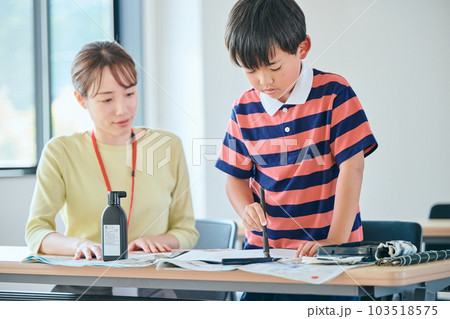 書道を練習する生徒と若い塾講師 103518575