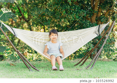 アウトドア・キャンプ場でハンモックに乗る子供（外遊び）の写真素材 
