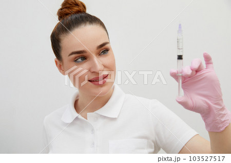 Cosmetologist holds syringe for injection with collagen hyaluronic filler for face or lips rejuvenation Cosmetologist holds syringe for injection with collagen hyaluronic filler for face or lips rejuvenation 103527517
