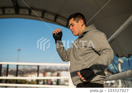 A man in a hoody trains in boxing at the stadium. A man in a hoody trains in boxing at the stadium. 103527827