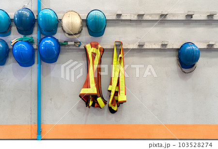 Safety vest and construction hardhat of supervisors and employees hang in front of the factory office shop for safety. Concept of work safety. Building industry. 103528274